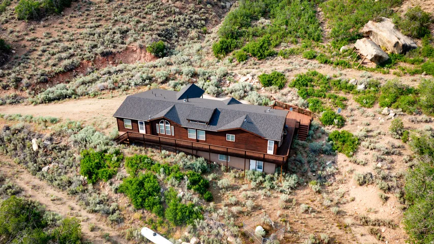 Wood-sided residence with multiple dormer windows, a full-length wooden deck, and a dark shingle roof
