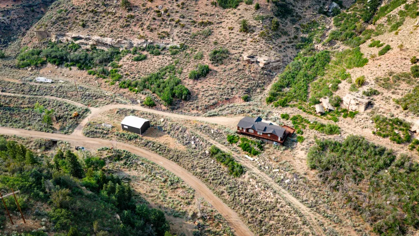 Mountain property with a multi-gabled residence, expansive surrounding terrain, additional outbuilding, and winding access roads