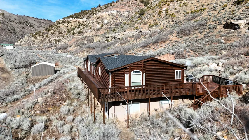 View of home's exterior featuring a deck with mountain view, a shingled roof, and log veneer siding