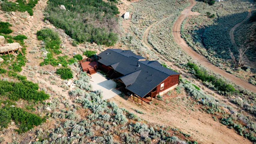 Wood-sided residence with dark shingle roofing, featuring a concrete driveway and multiple wooden deck areas