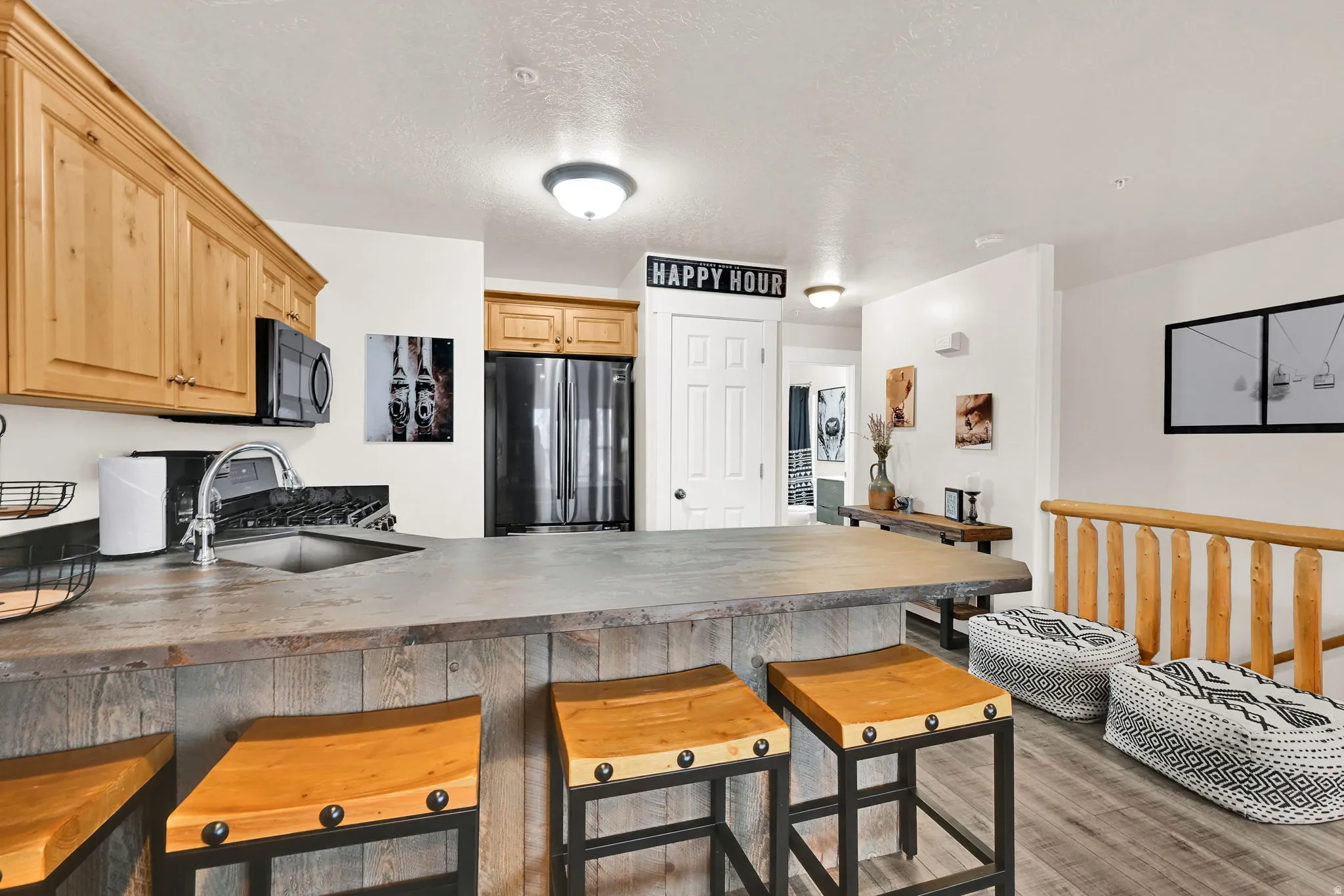 Kitchen featuring a peninsula, freestanding refrigerator, light wood finished floors, a kitchen breakfast bar, and light wood finish cabinets