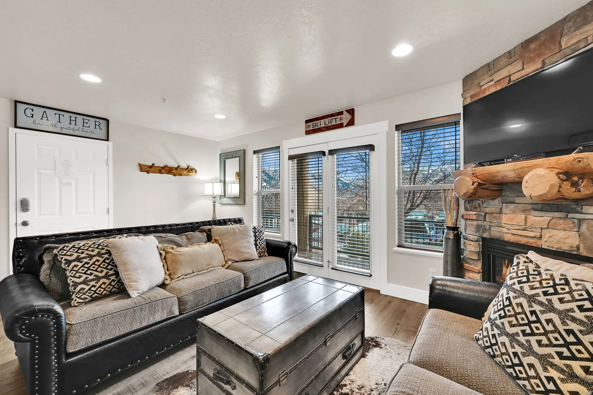 Living room with wood finished floors, a stone fireplace, and recessed lighting