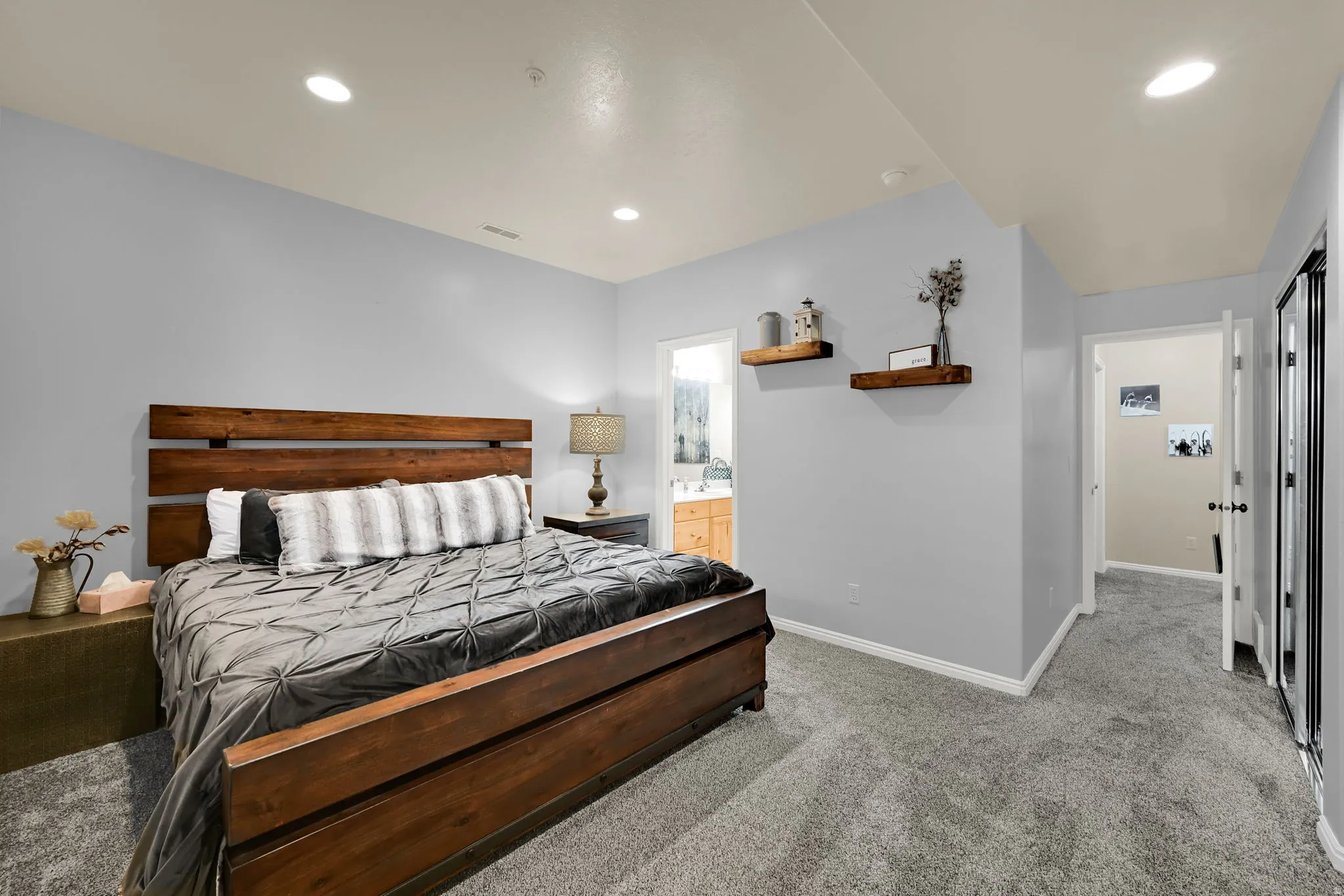 Bedroom with light colored carpet, recessed lighting, and ensuite bathroom
