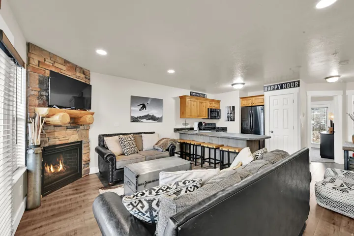Living room featuring a stone fireplace, recessed lighting, and light wood-style flooring