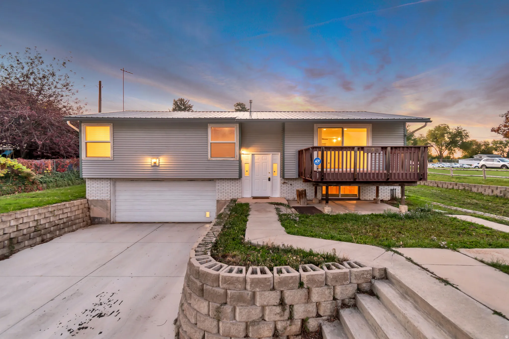 Split foyer home featuring a garage, brick siding, concrete driveway, and a metal roof