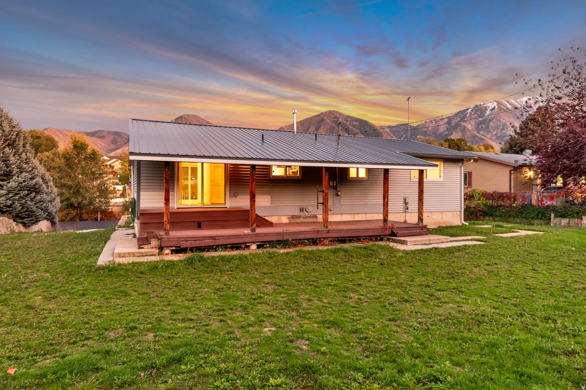 Back of property at dusk featuring a mountain view, a yard, and a metal roof