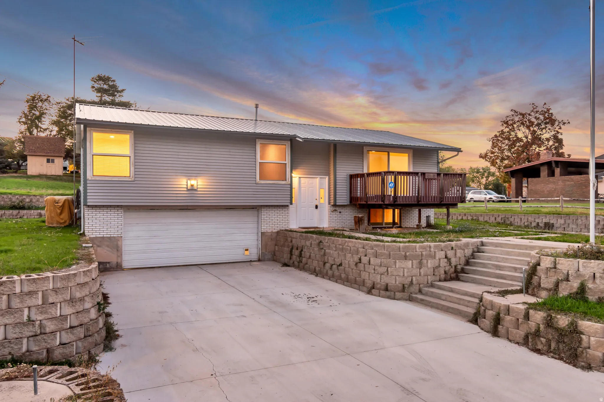 View of front of property with brick siding, a garage, driveway, and a metal roof