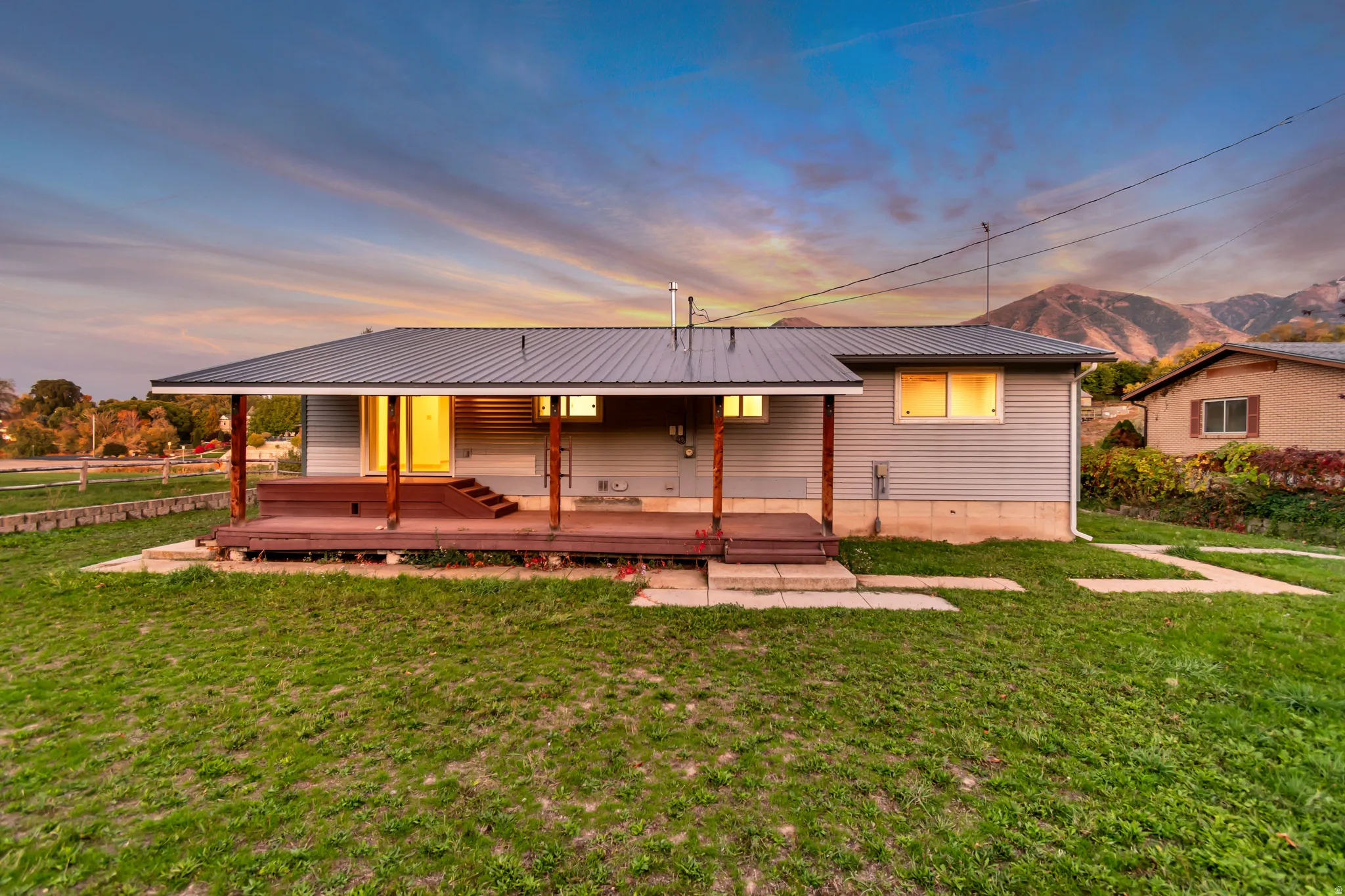 Back of house at dusk featuring a metal roof, a mountain view, and covered porch