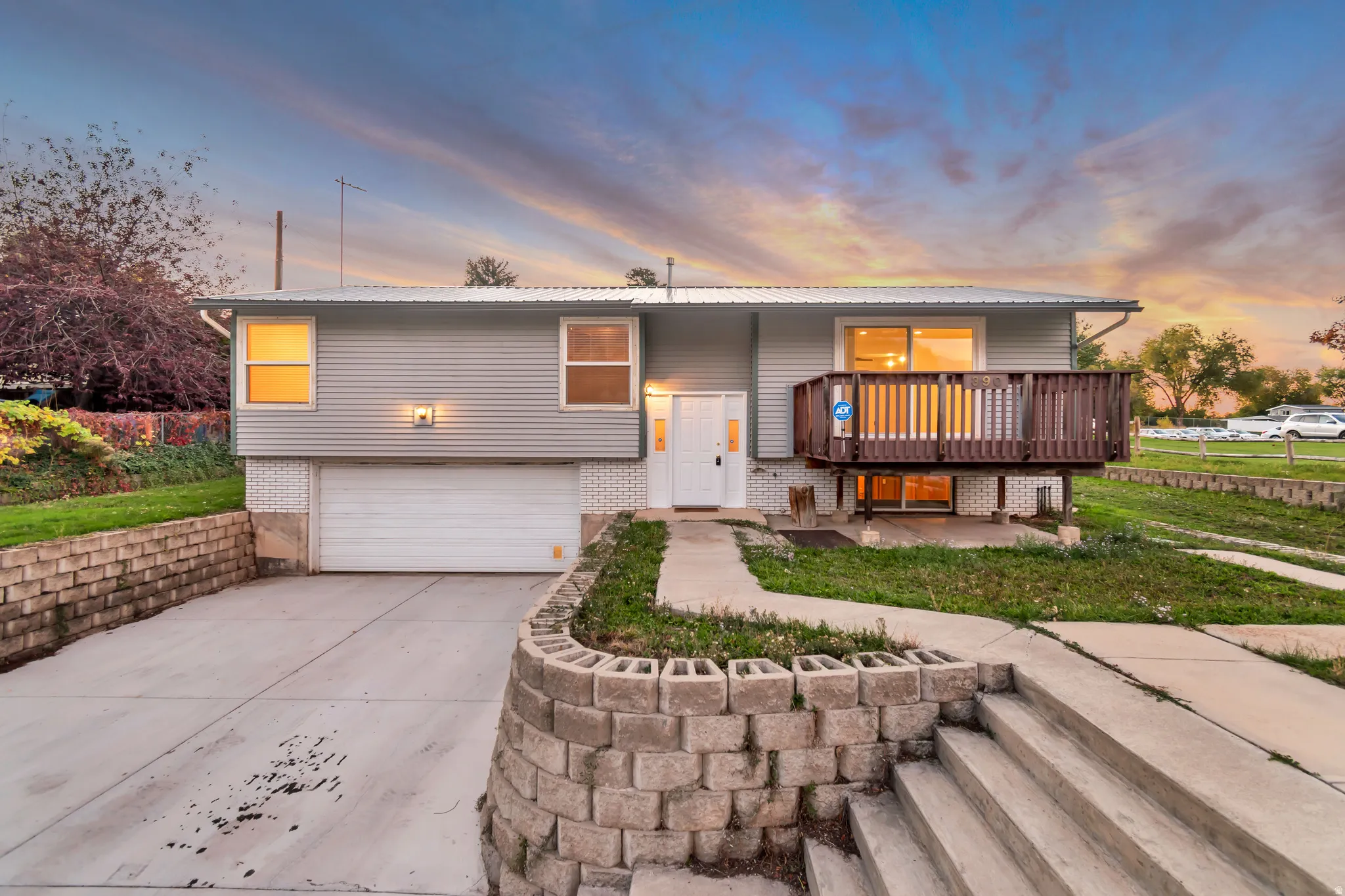 Raised ranch with brick siding, a garage, driveway, and a metal roof