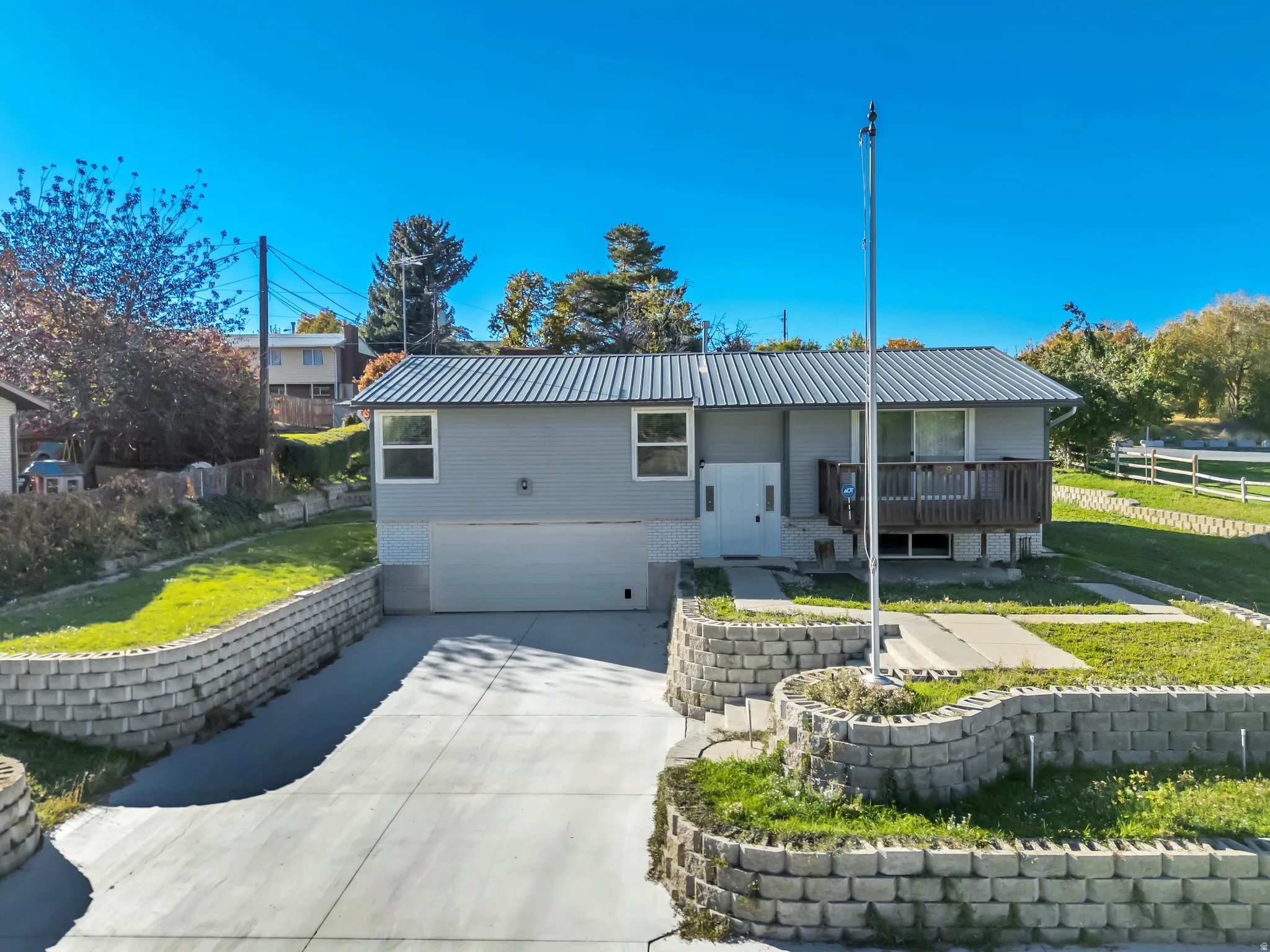 View of front of house with an attached garage, a metal roof, driveway, and brick siding