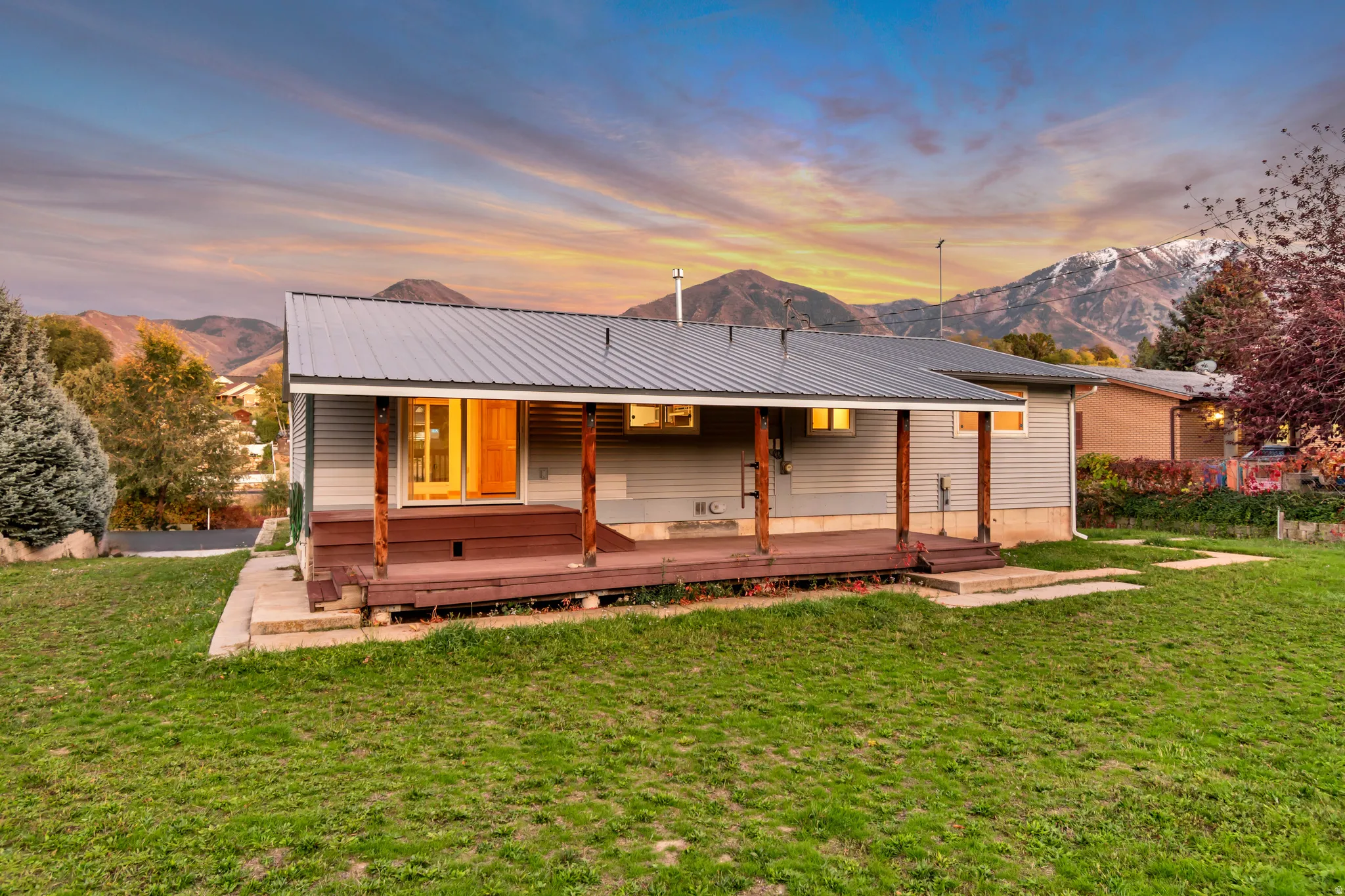 Back of property at dusk featuring a mountain view, a yard, and a metal roof