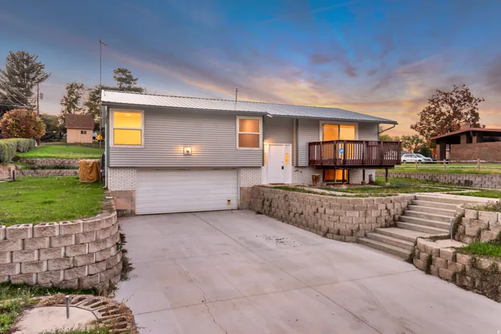 Split foyer home with a garage, brick siding, concrete driveway, and a metal roof
