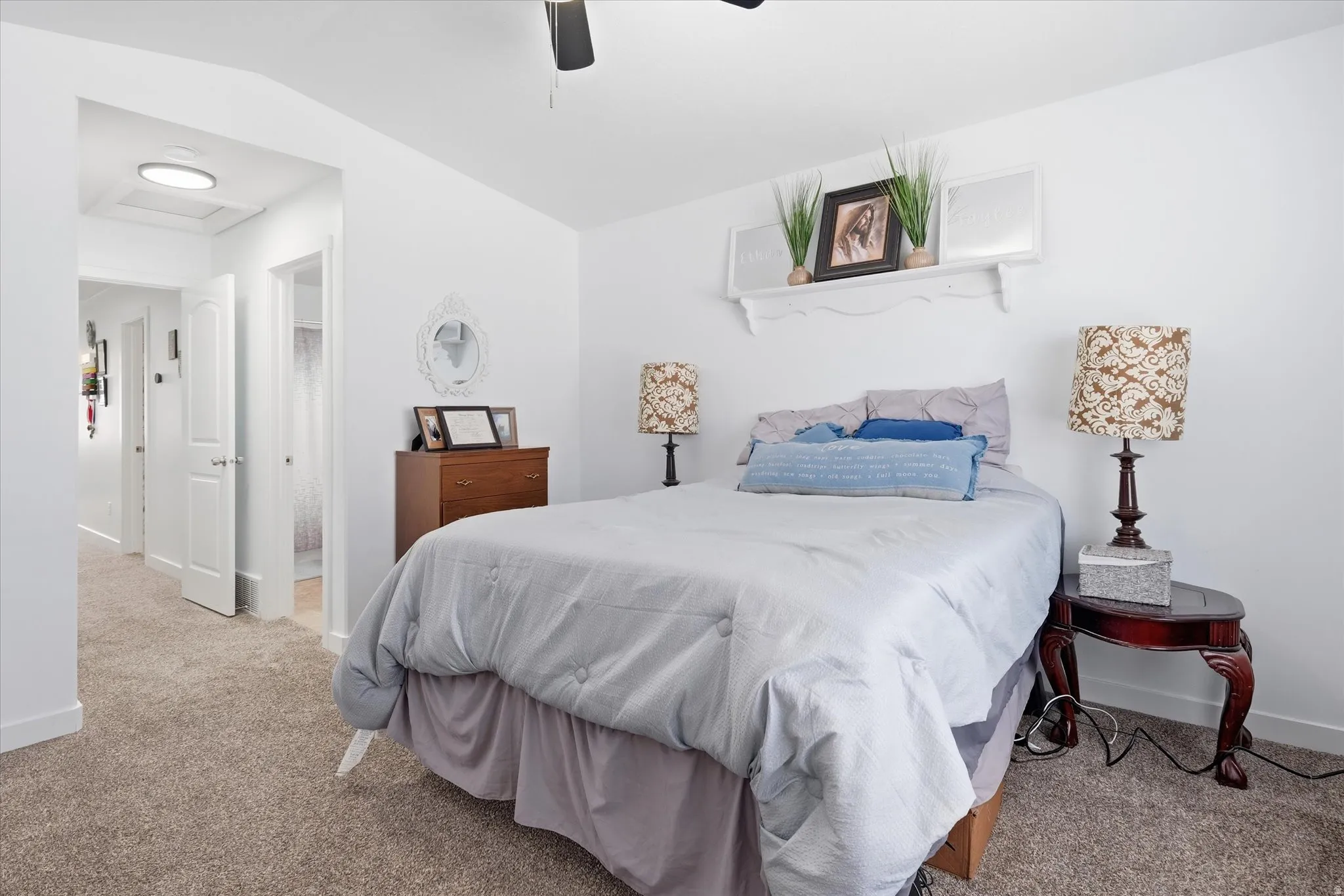 Bedroom with lofted ceiling, light colored carpet, ensuite bathroom, and a ceiling fan