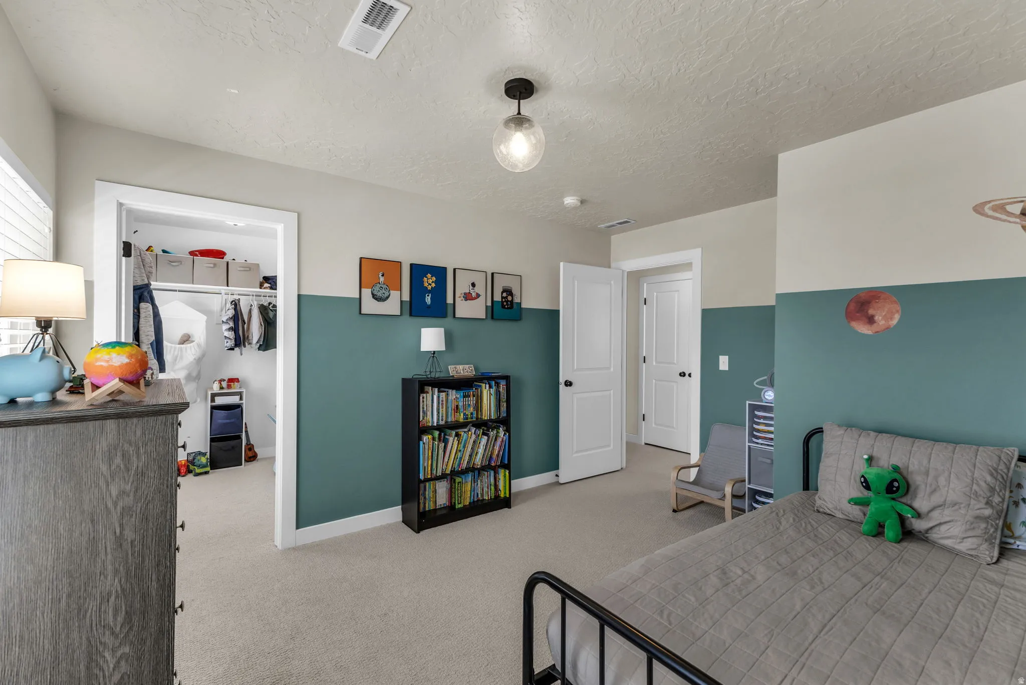 Bedroom with a walk in closet, light colored carpet, and a textured ceiling