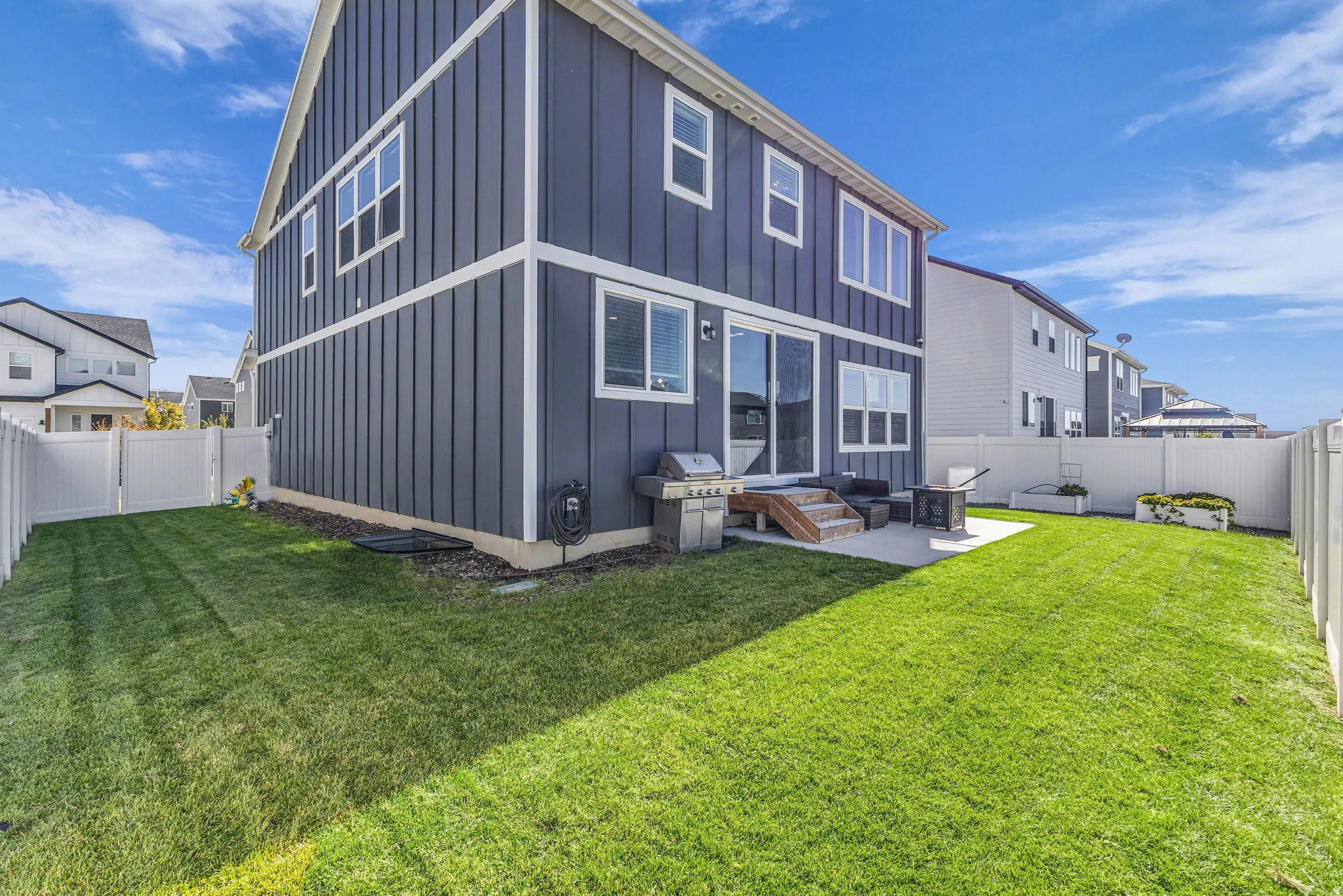 Back of house with board and batten siding, a fenced backyard, and a patio