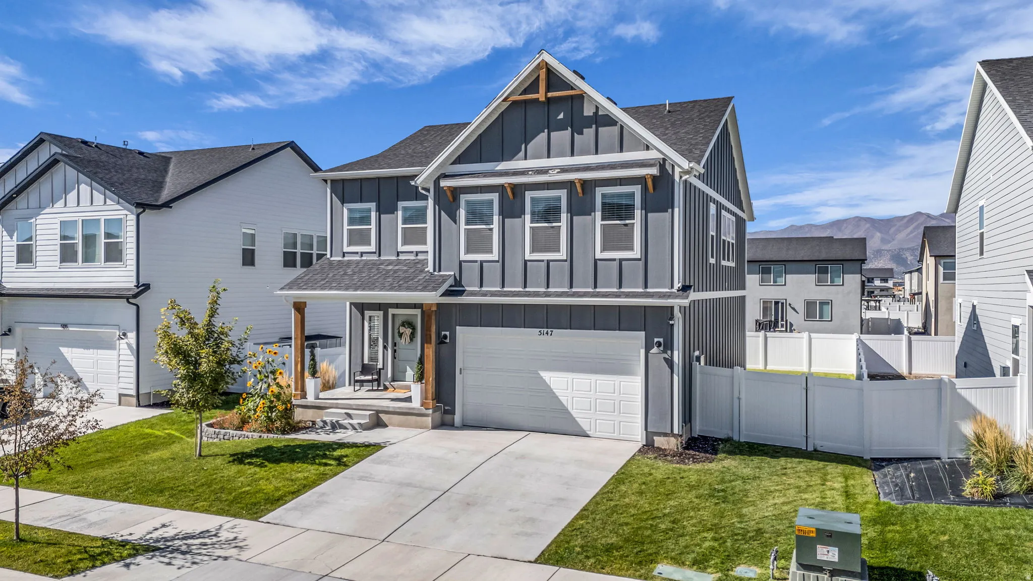 View of front facade with board and batten siding, a garage, concrete driveway, a residential view, and a mountain view