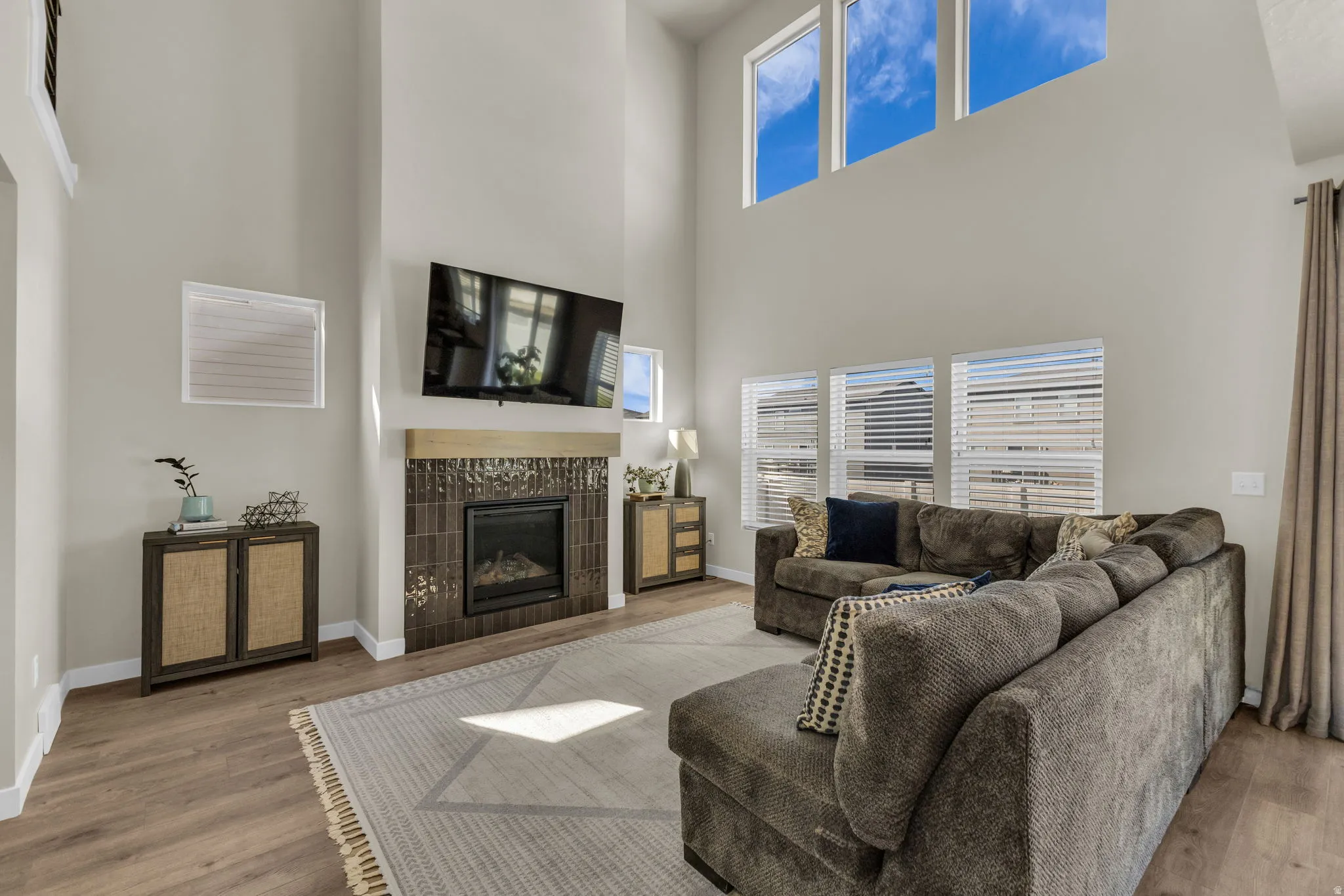 Living area featuring a tile fireplace, wood finished floors, a high ceiling, and plenty of natural light