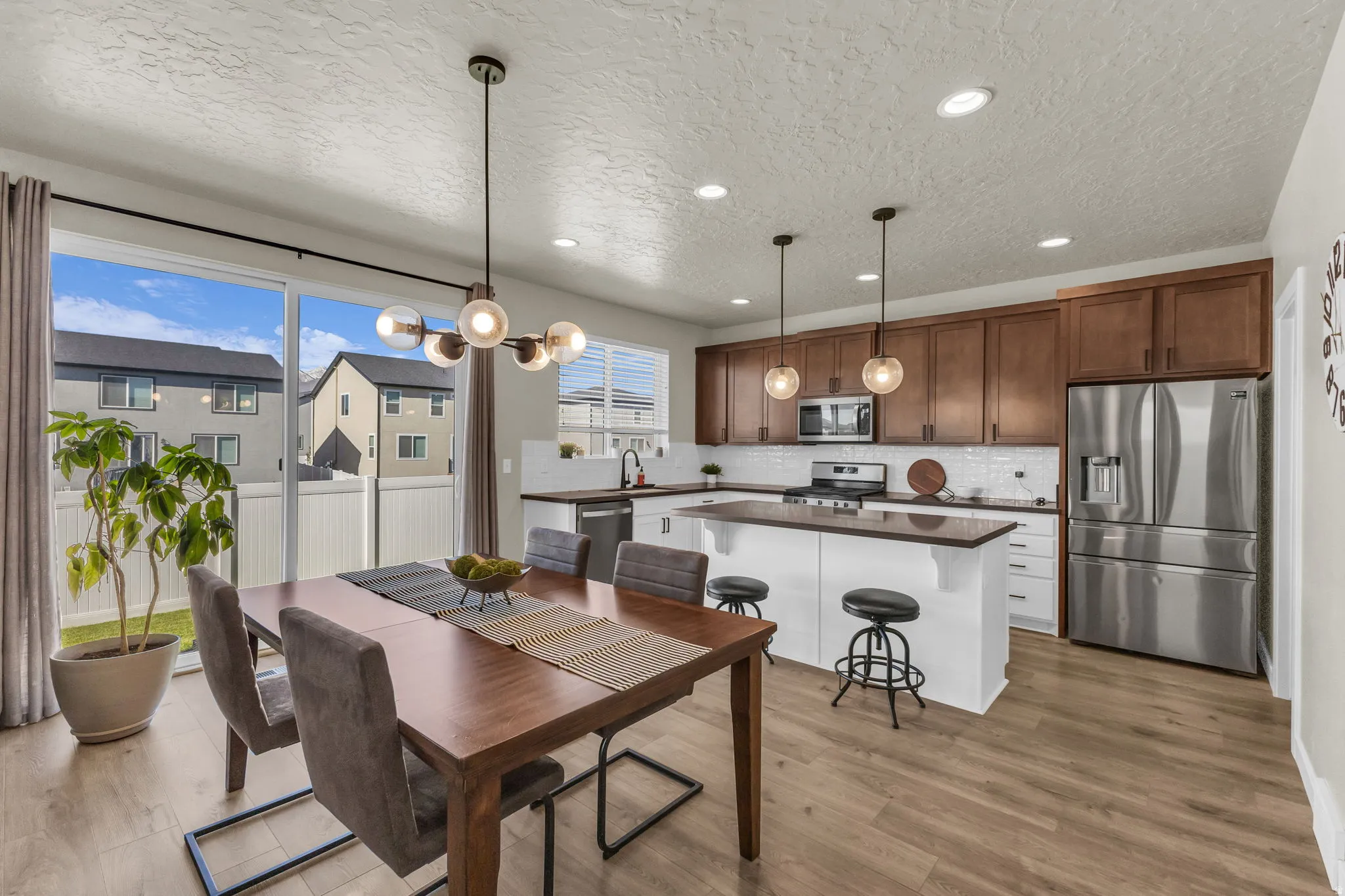 Dining area featuring light wood-type flooring, a textured ceiling, and hanging lights