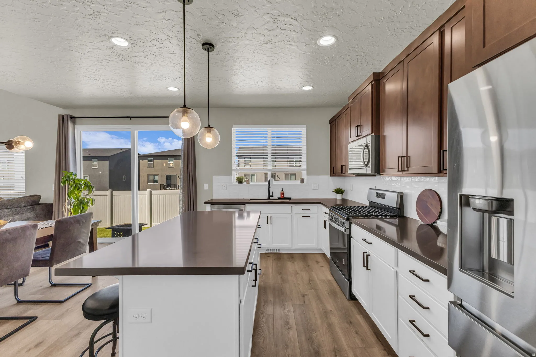 Kitchen featuring dark countertops, stainless steel appliances, a kitchen breakfast bar, backsplash, and a textured ceiling