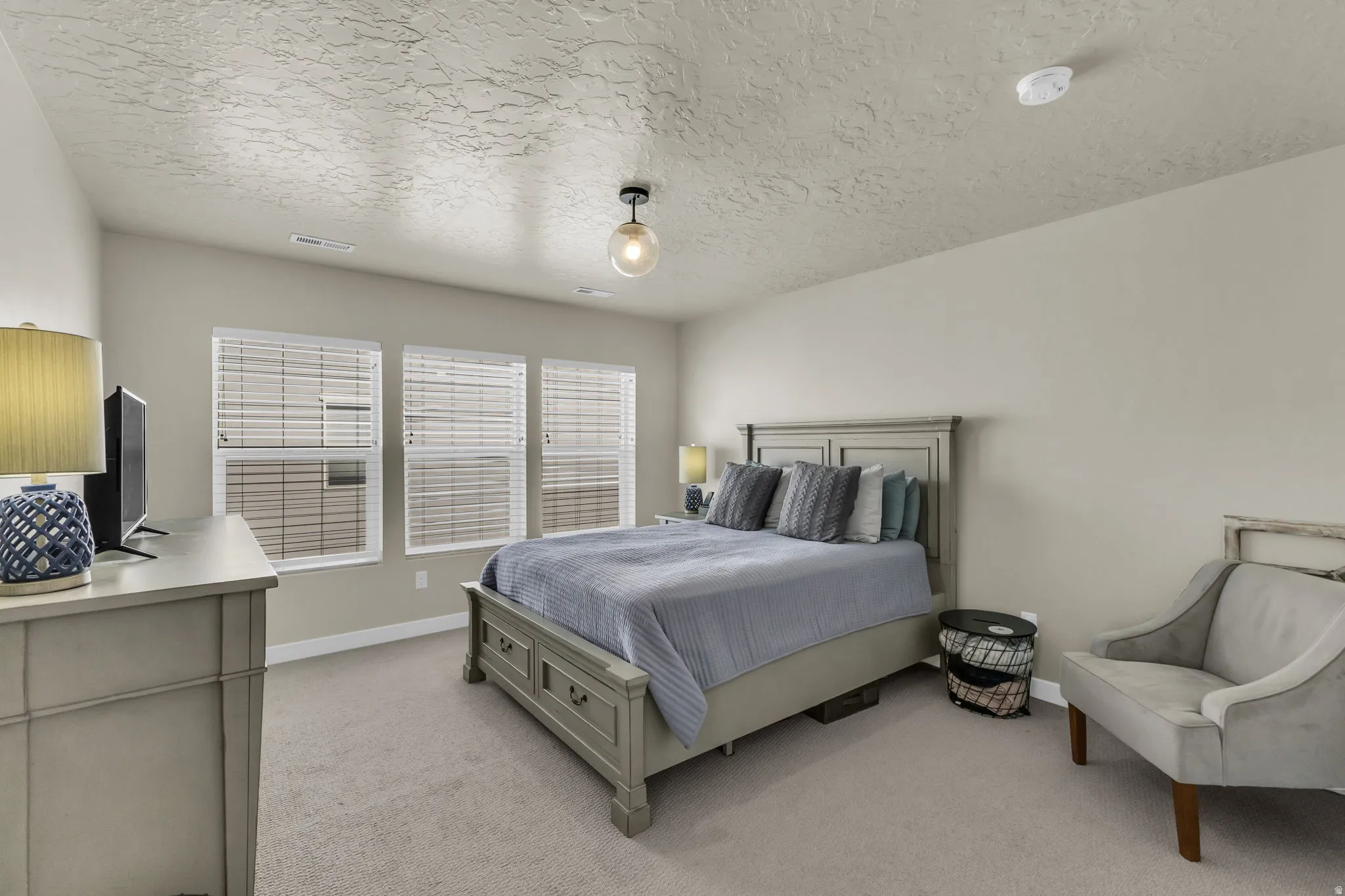 Bedroom with light carpet and a textured ceiling