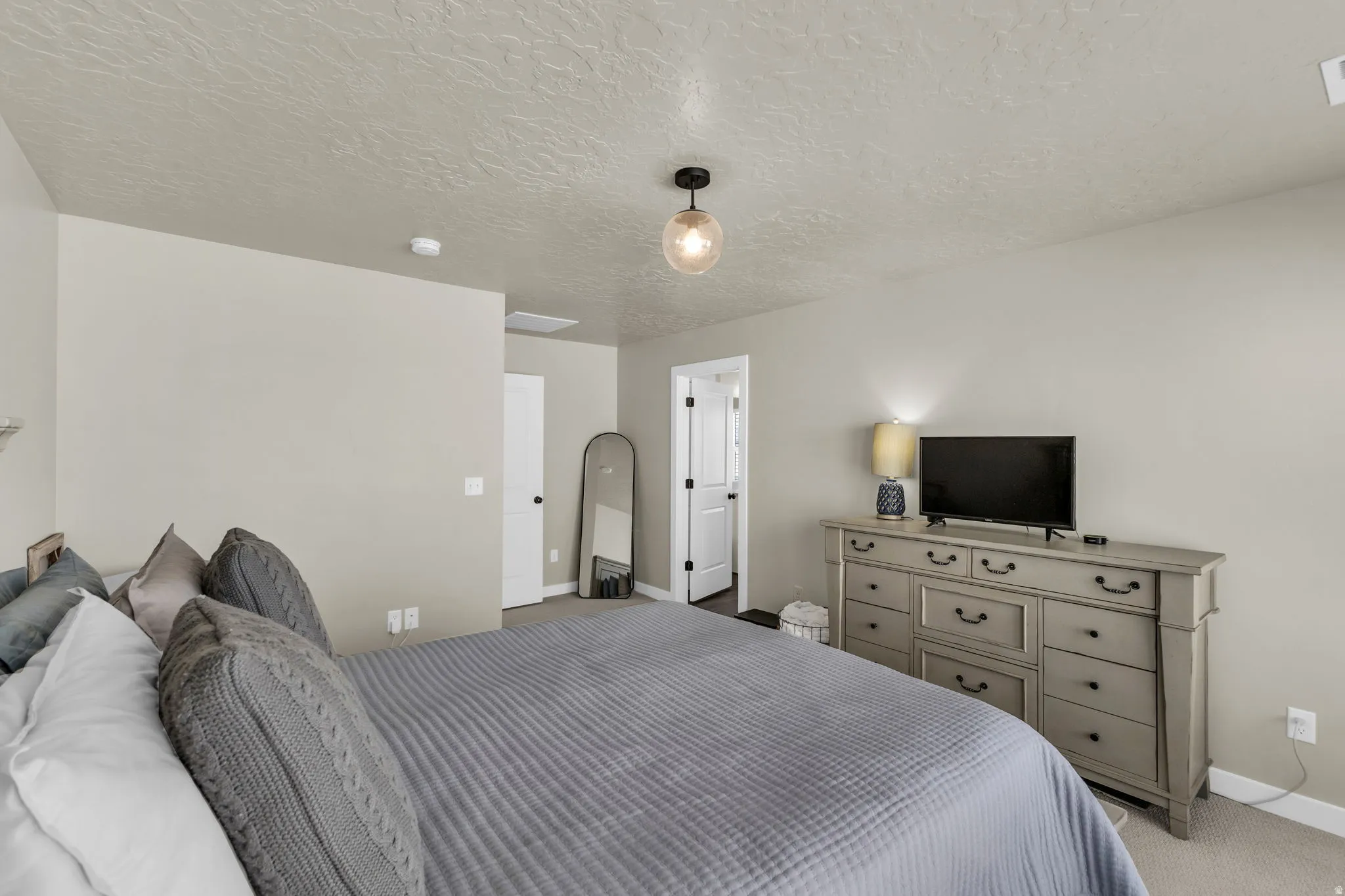 Carpeted bedroom featuring a textured ceiling and baseboards