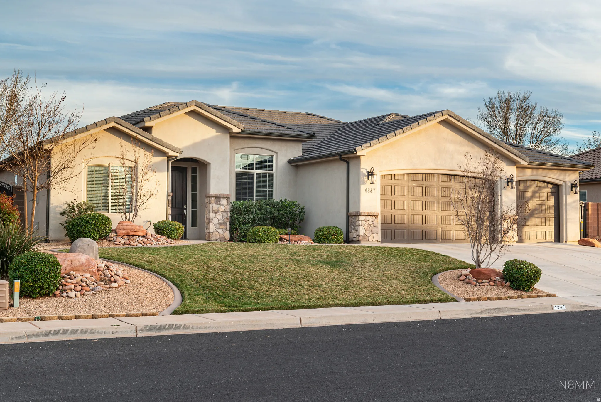 View of front of house with an attached garage, driveway, stucco siding, and a front yard