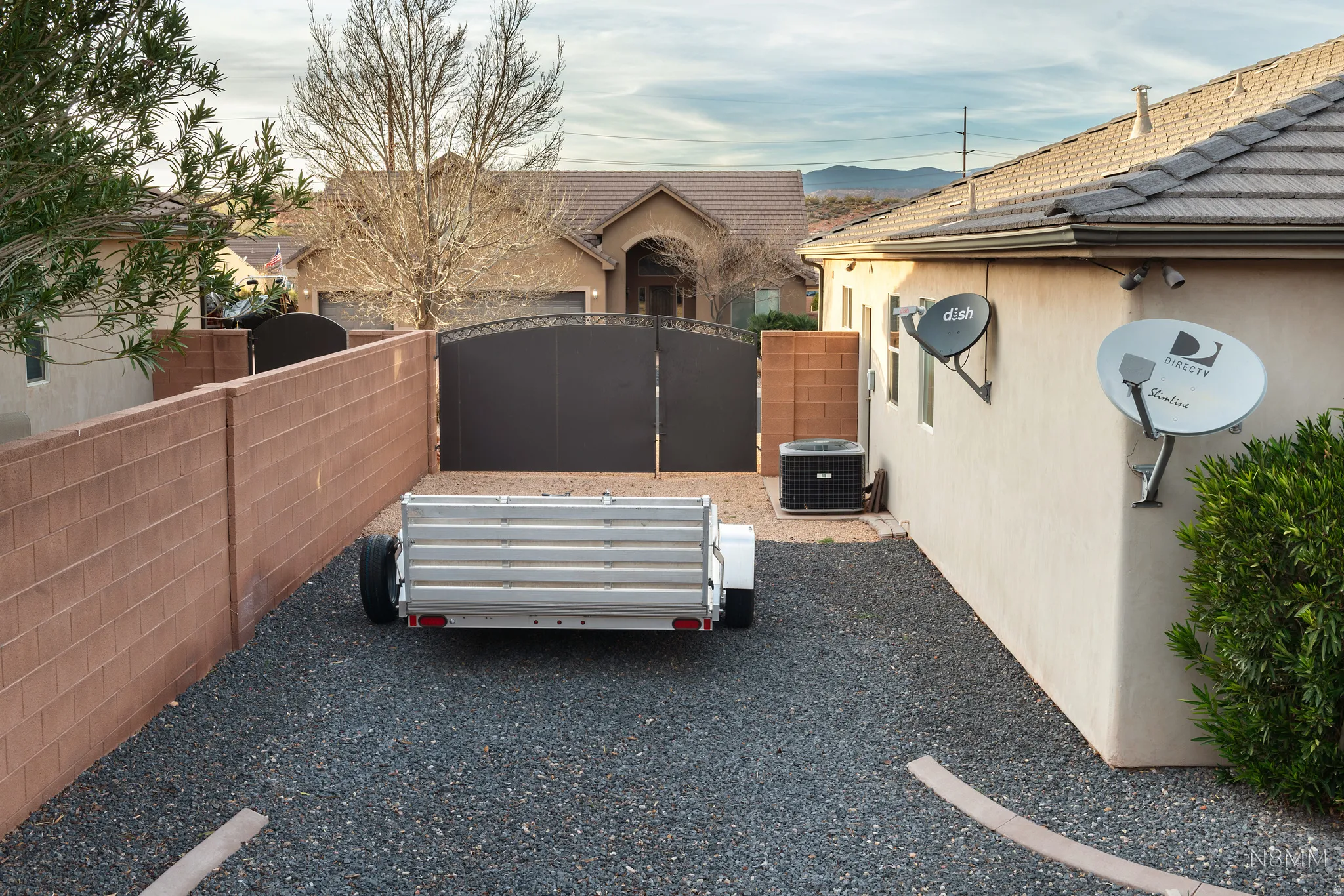View of side of property with a tiled roof, stucco siding, and a gate