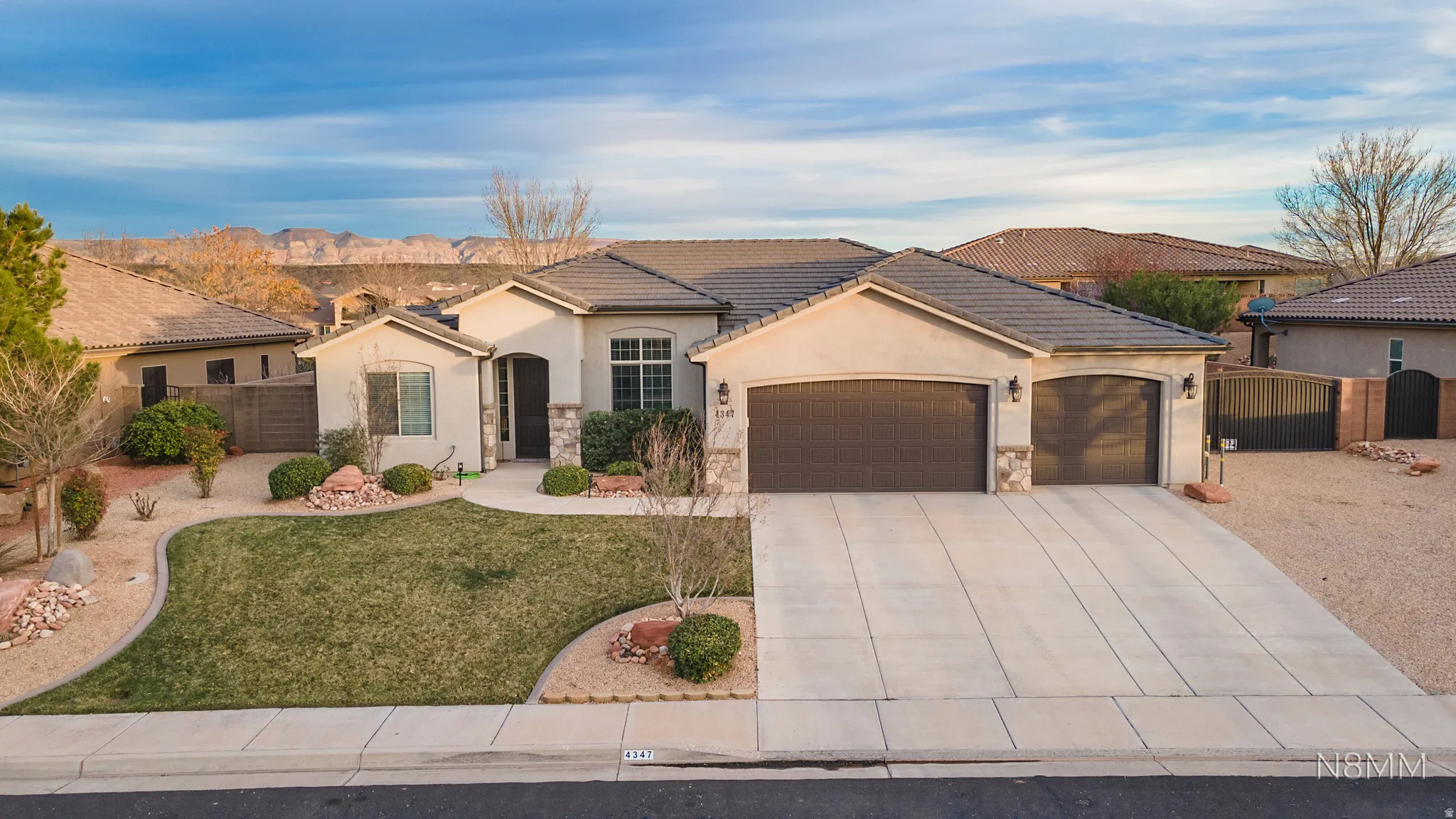 Mediterranean / spanish-style home featuring stone siding, a garage, stucco siding, concrete driveway, and a gate