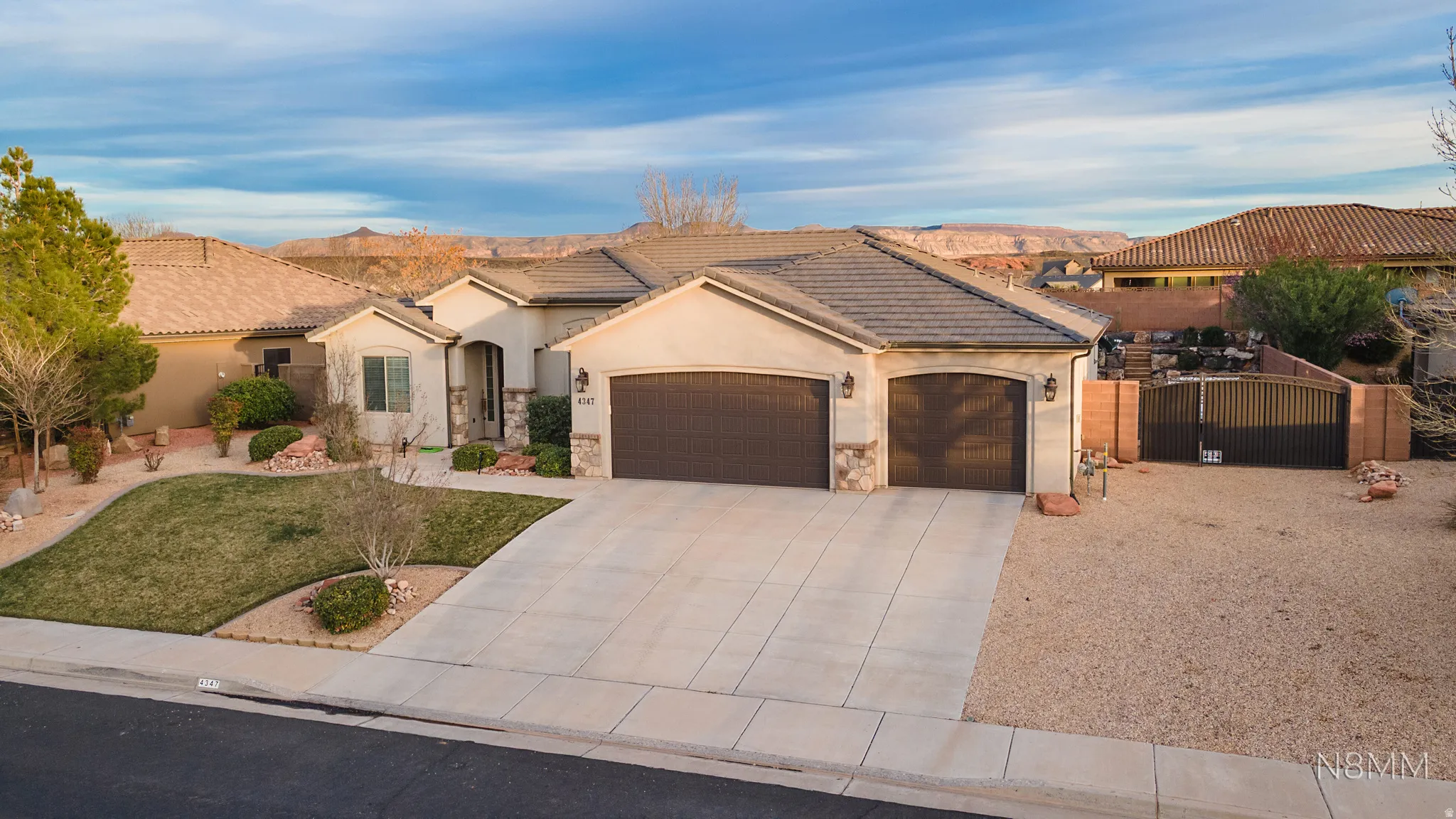 View of front of house featuring a garage, driveway, stucco siding, and stone siding