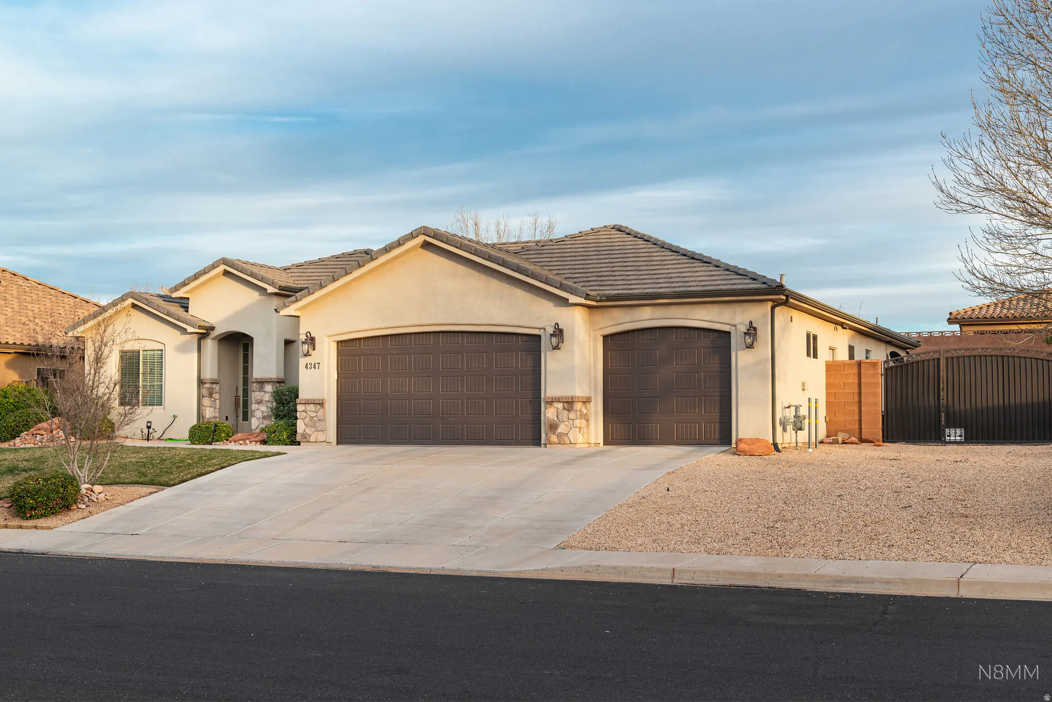 View of front of property featuring a garage, concrete driveway, stucco siding, and stone siding