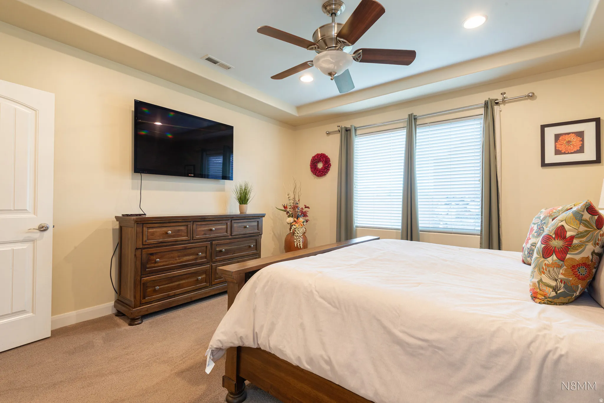 Bedroom featuring a raised ceiling, light carpet, ceiling fan, and recessed lighting