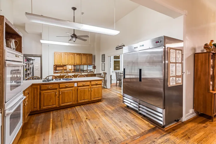 Kitchen featuring stainless steel refrigerator, dark wood-style flooring, double oven, wood finish cabinetry, and lofted ceiling