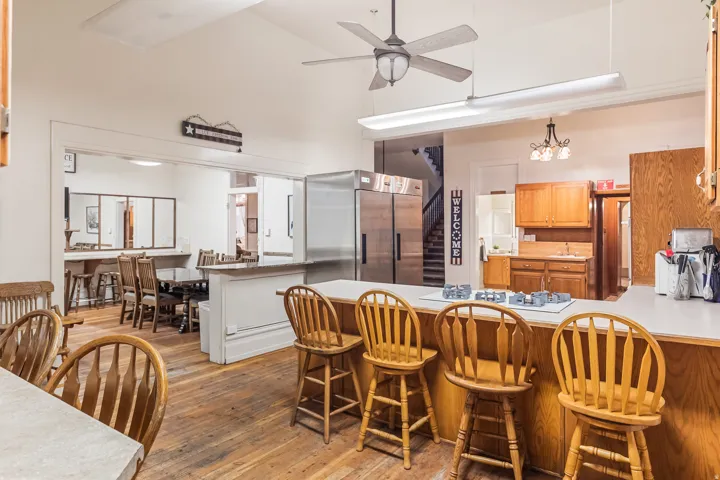 Kitchen with a peninsula, light countertops, high quality fridge, a breakfast bar, and vaulted ceiling