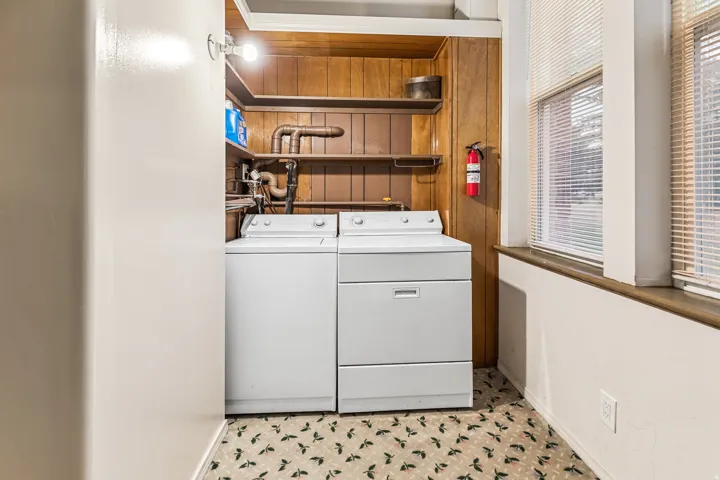 Laundry area featuring independent washer and dryer and wood walls