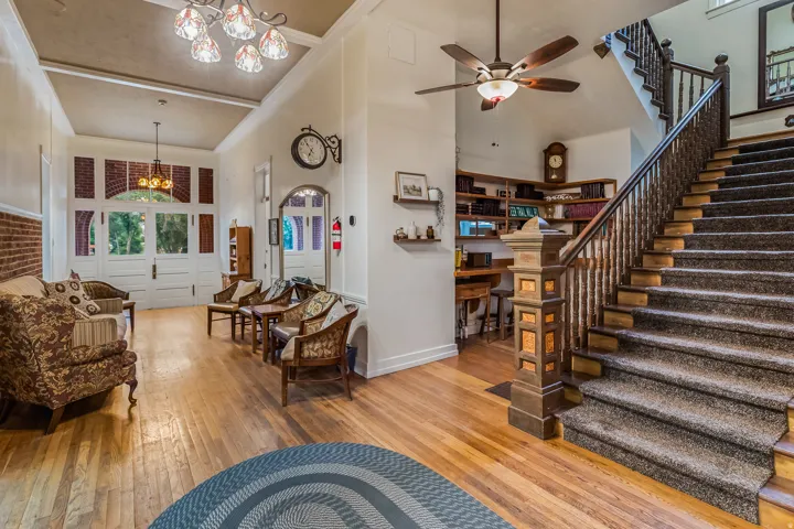 Living area with a chandelier, a high ceiling, light wood finished floors, and a ceiling fan