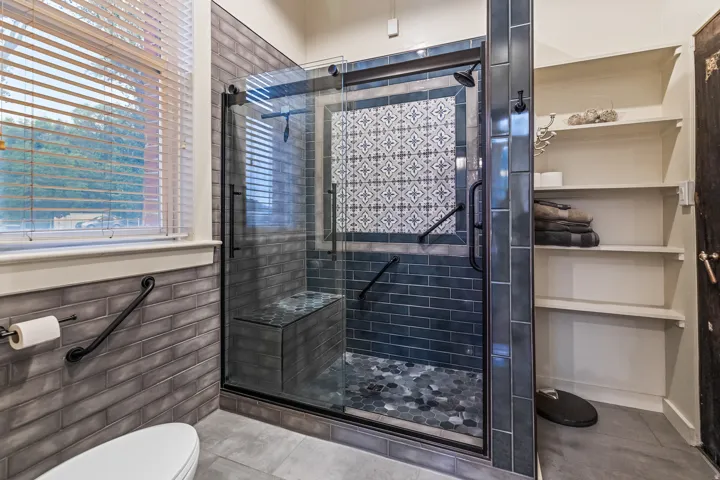 Bathroom featuring a shower stall, tile patterned flooring, and tile walls