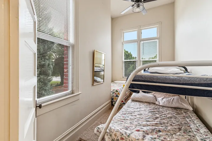 Carpeted bedroom with ceiling fan and baseboards