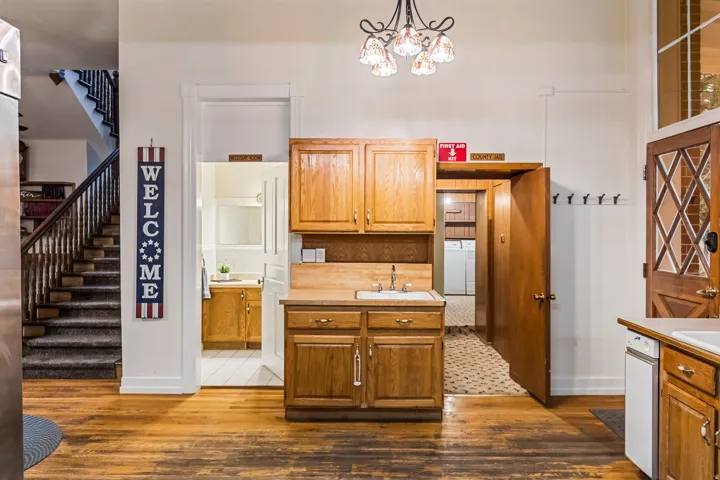 Kitchen with light countertops, wood finish cabinets, dark wood-type flooring, and suspended lighting