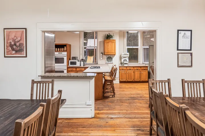 Kitchen with light wood-style floors, white appliances, wood finish cabinetry, and light stone counters