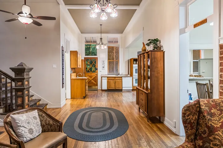 Living area with ceiling fan, light wood finished floors, a chandelier, and a high ceiling