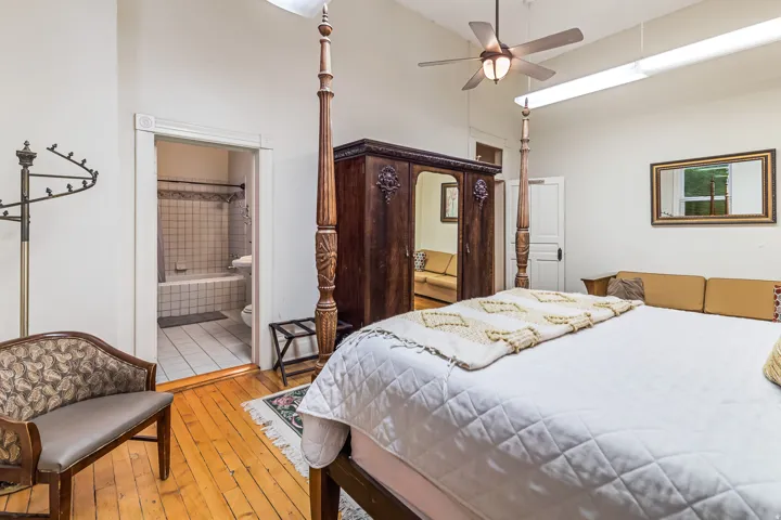 Bedroom featuring a high ceiling, light wood-style floors, a ceiling fan, and ensuite bath