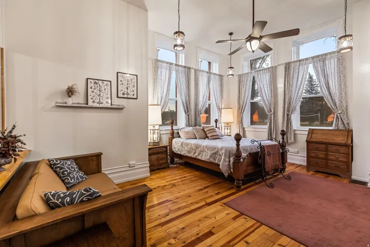 Bedroom featuring hardwood / wood-style flooring, multiple windows, and a ceiling fan