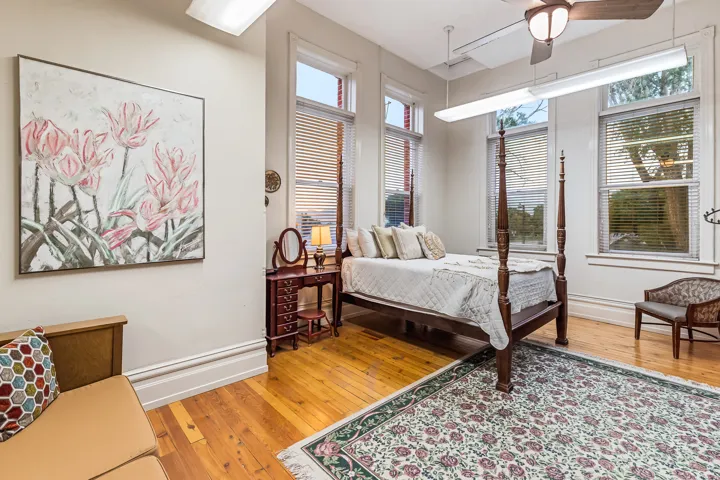 Bedroom featuring light wood-style floors, ceiling fan, and multiple windows