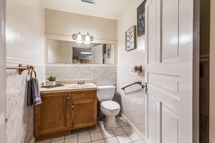 Half bath with vanity, light tile patterned floors, tile walls, and a wainscoted wall