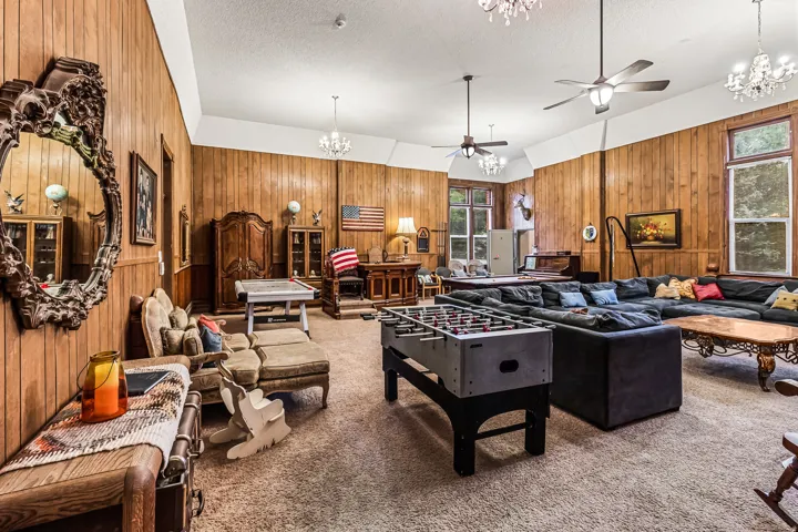 Playroom with hanging lights, wood walls, ceiling fan, carpet floors, and a textured ceiling