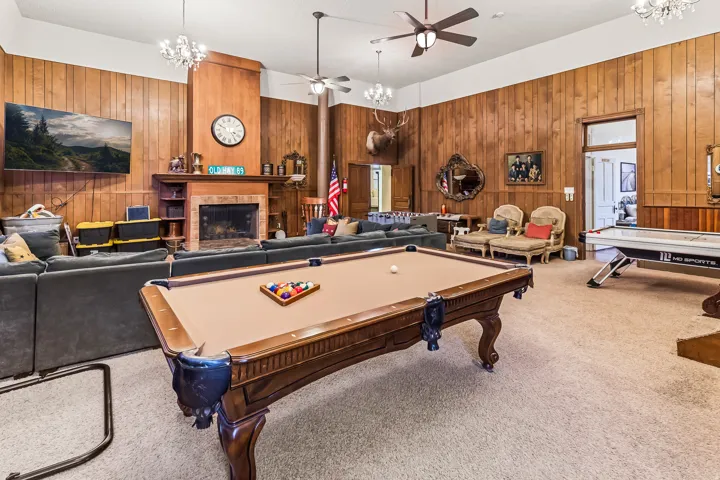 Recreation room with hanging lights, billiards table, carpet floors, wooden walls, and ceiling fan