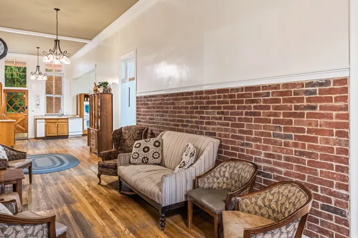 Living area with brick wall, light wood-style flooring, and a chandelier