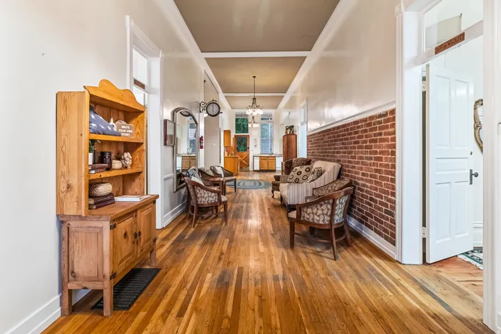 Sitting room with brick wall, light wood-style flooring, and a chandelier