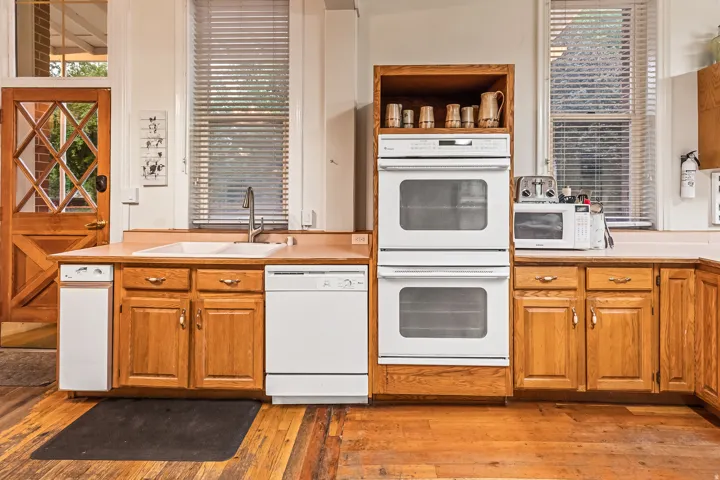 Kitchen featuring white appliances, open shelves, light countertops, light wood finished floors, and wood finish cabinetry