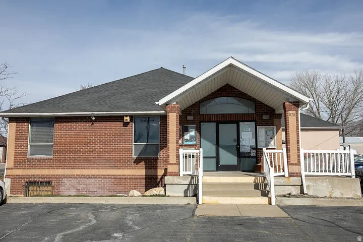 View of front of property featuring brick siding and roof with shingles